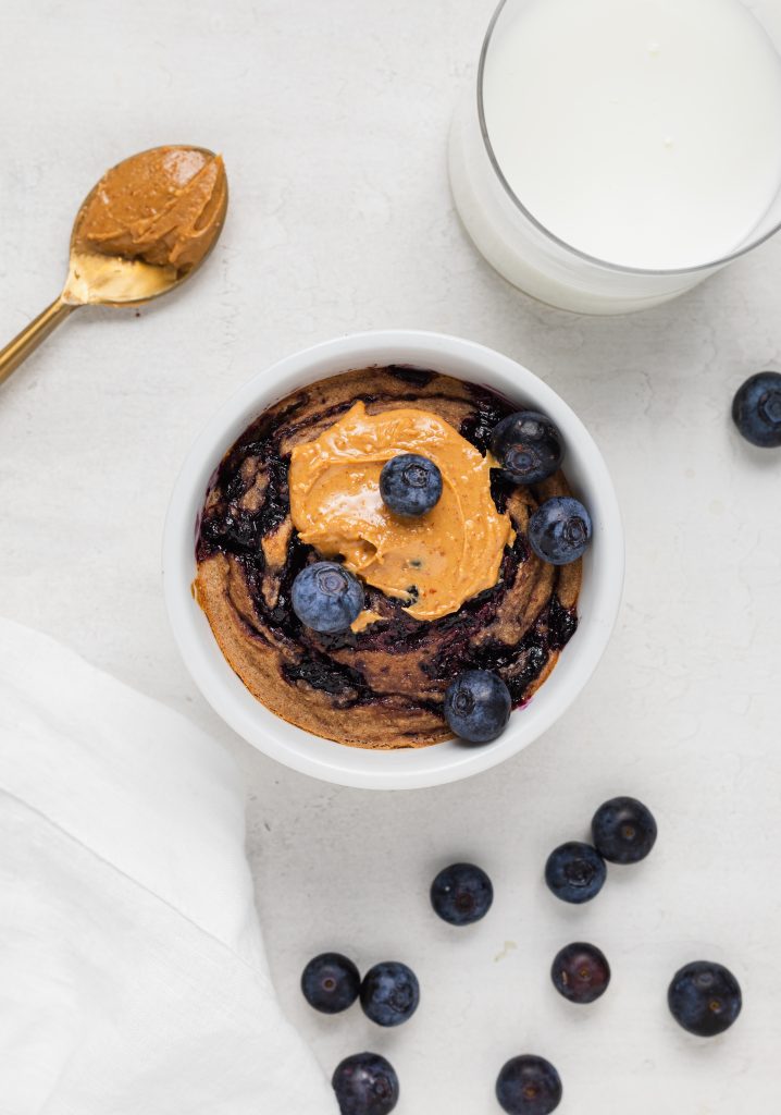 overhead image of peanut butter and jelly baked oats with milk and blueberries on the side.