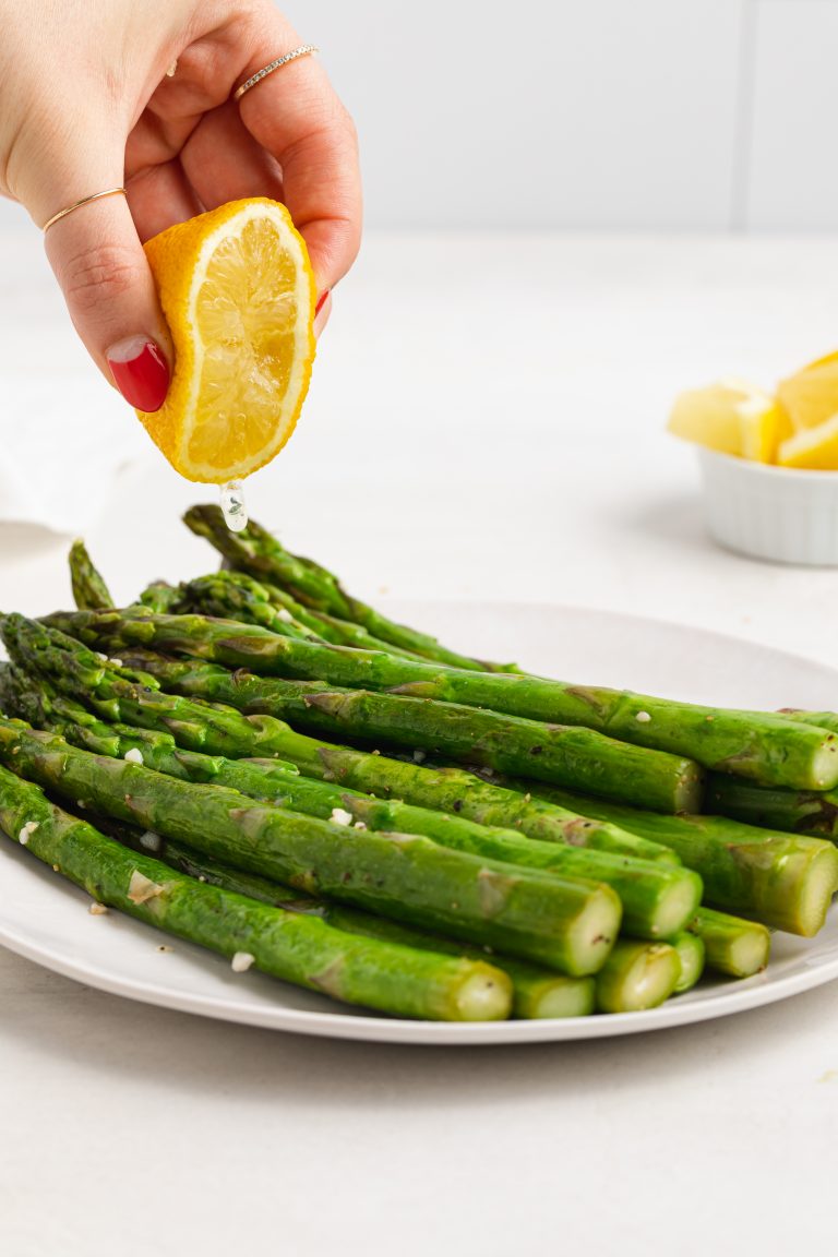 fresh lemon being squeezed over sous vide asparagus