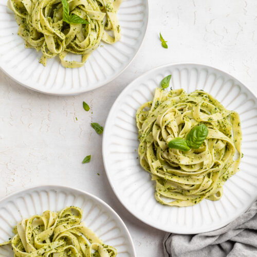 overhead image of three bowls of vegan pesto pasta.