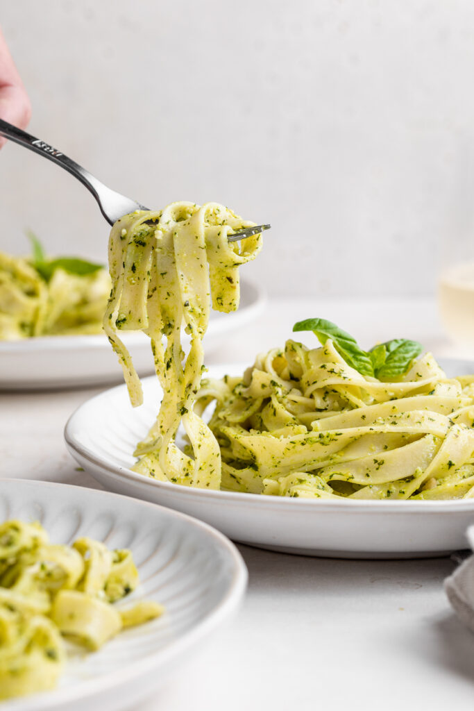 vegan pesto pasta being lifted out of a bowl with a fork.