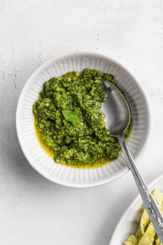 overhead image of vegan pesto in a bowl with a spoon.
