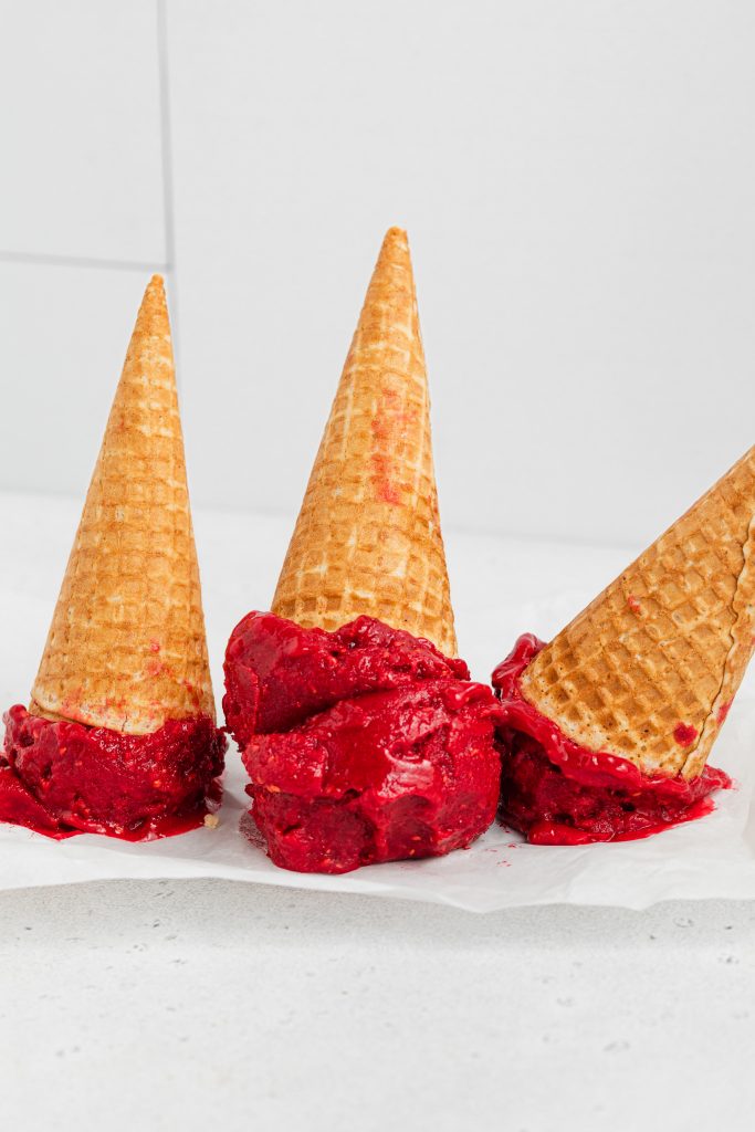 three upside down cones of vegan raspberry sorbet on parchment paper
