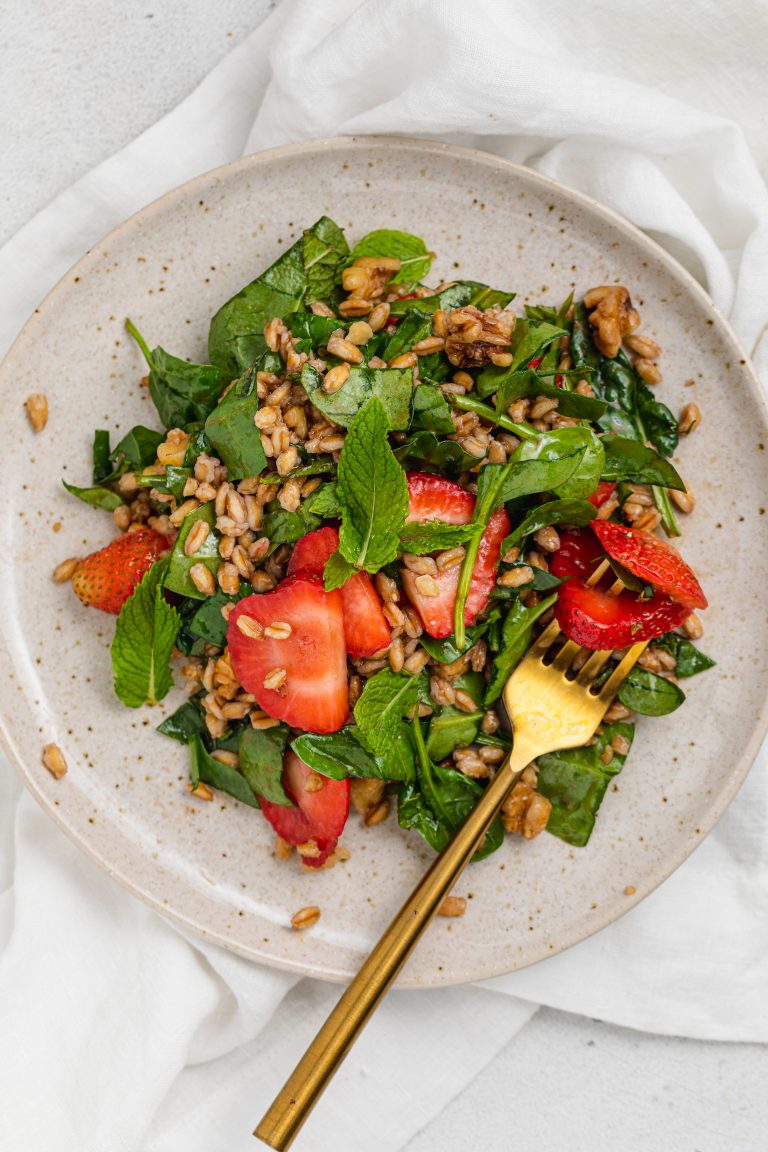 overhead image of strawberry spinach salad on a plate with a fork