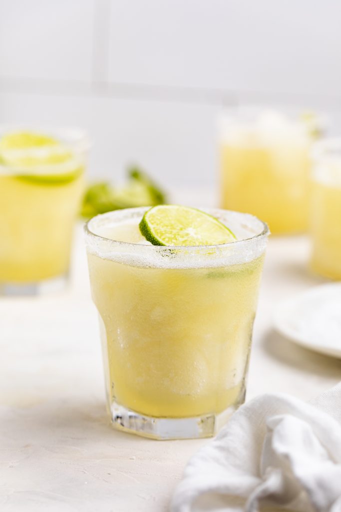 glasses of frozen margaritas with limes on top