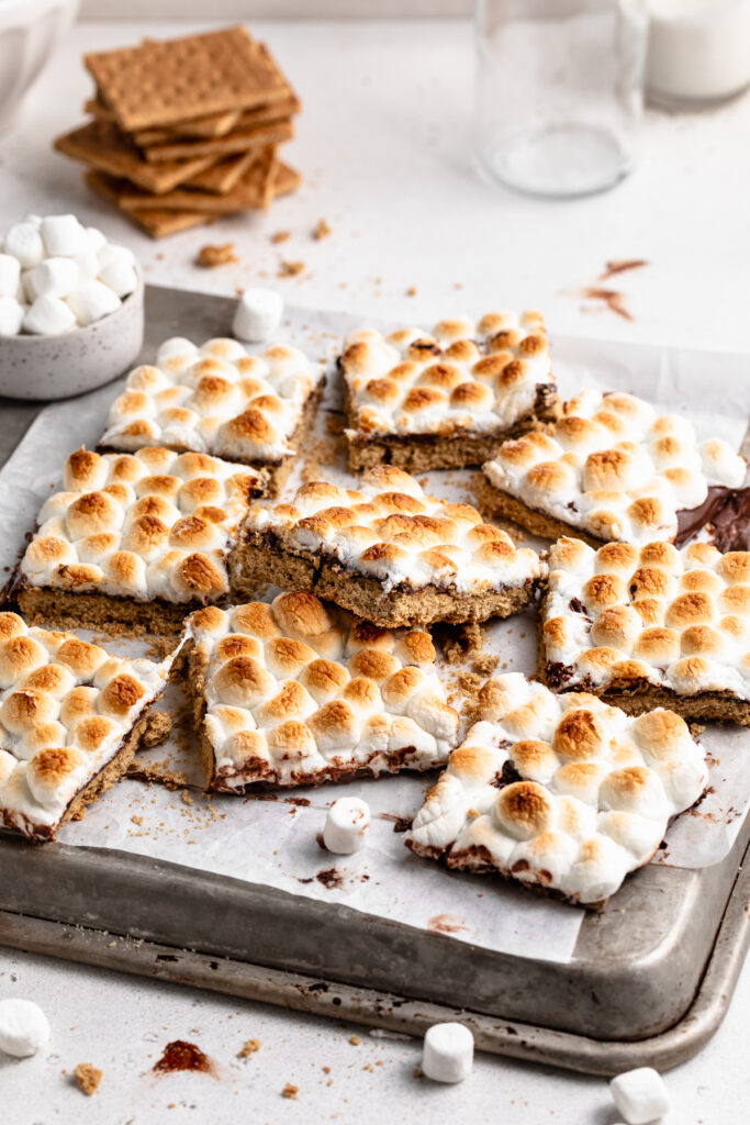s'mores bars on a baking sheet with graham crackers on the side.