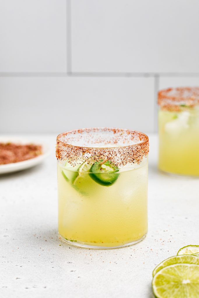 two spicy cucumber margaritas with spicy salt rim on the side