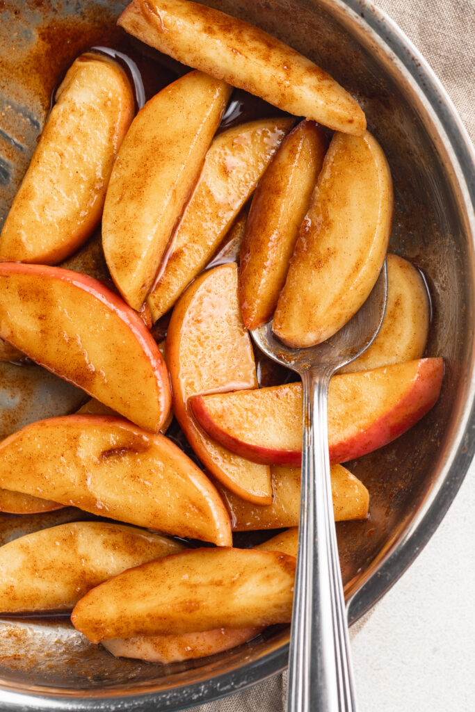 healthier caramelized apples in a skillet with a spoon.