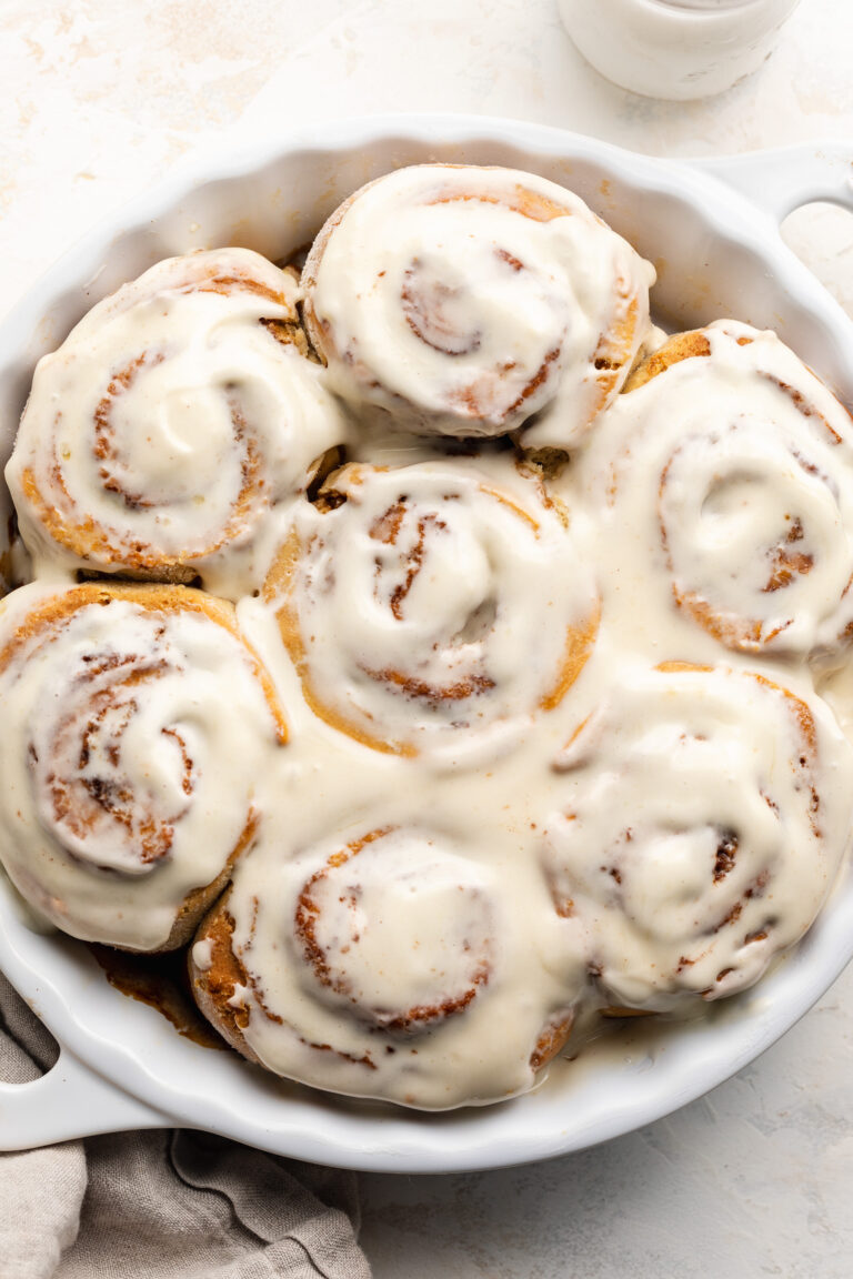 Overhead image of gluten-free cinnamon rolls in a baking dish with cream cheese frosting on top.
