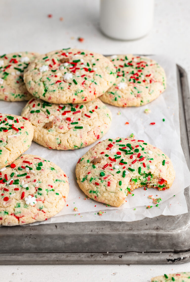 gluten-free christmas cookies on a baking sheet, one with a bite taken out.
