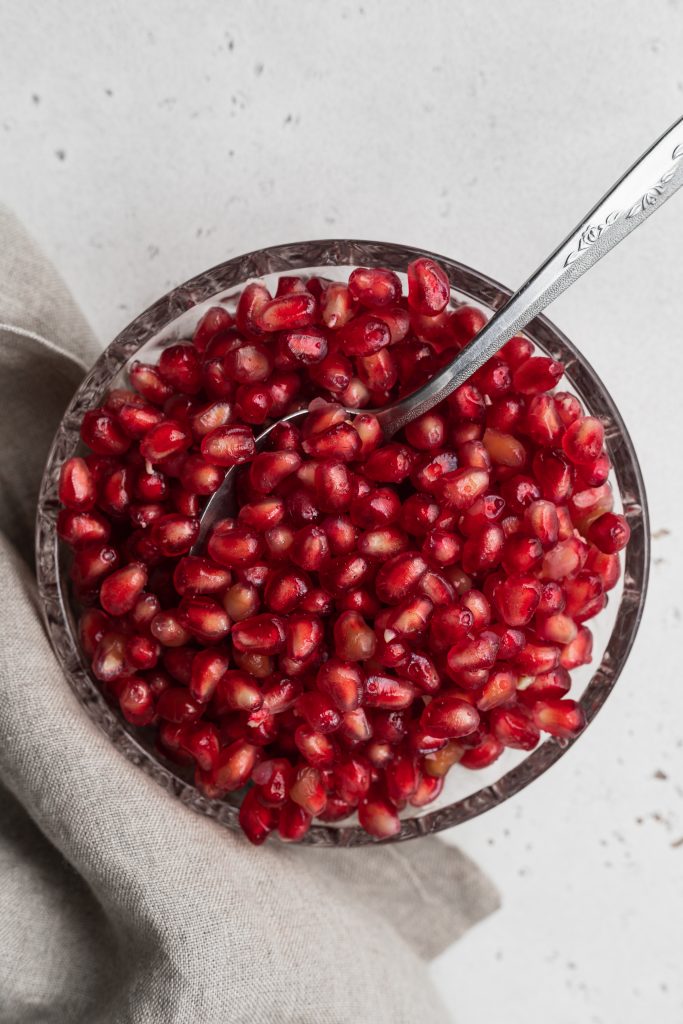 pomegranate seeds in a bowl with a spoon