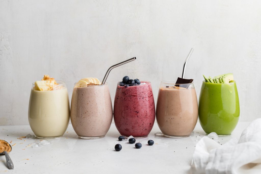 all 5 smoothies lined up in glasses with toppings on each
