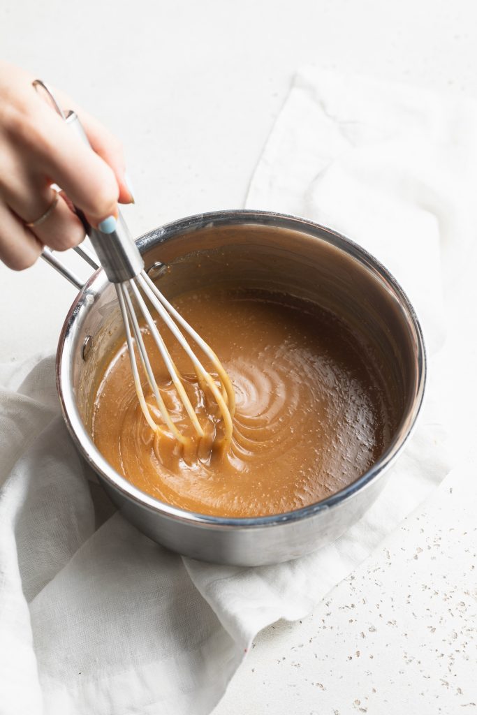 vegan caramel sauce being whisked in a saucepan