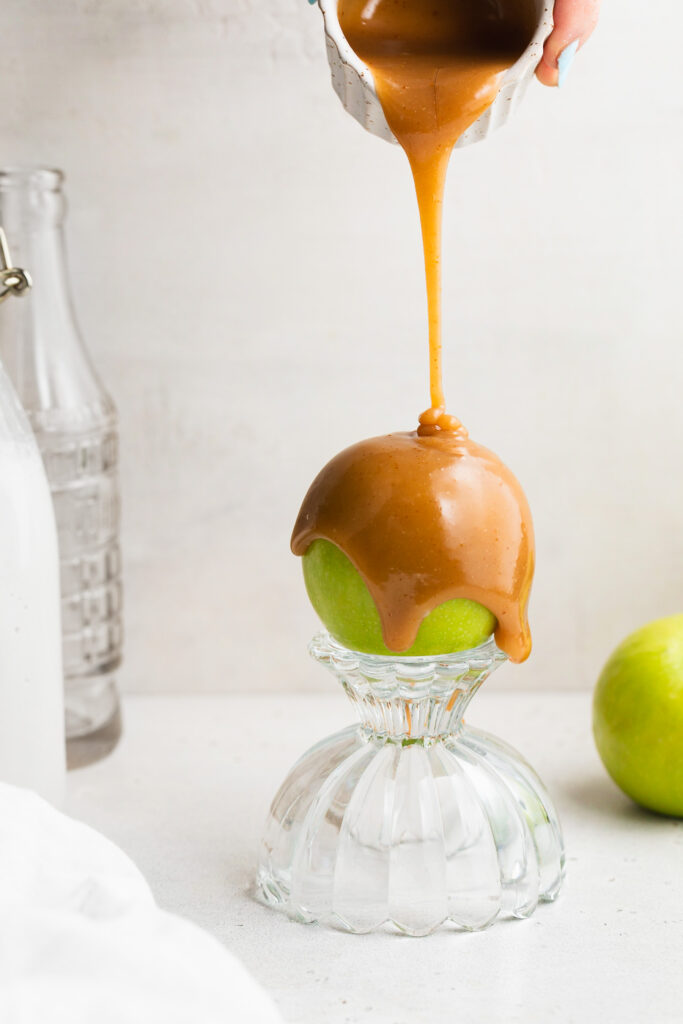 3 ingredient vegan caramel sauce being poured over a green apple.