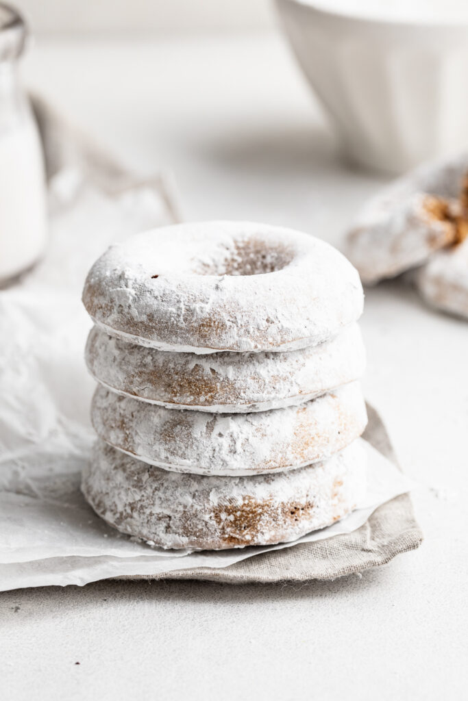 a stack of gluten-free donuts covered in powdered sugar.
