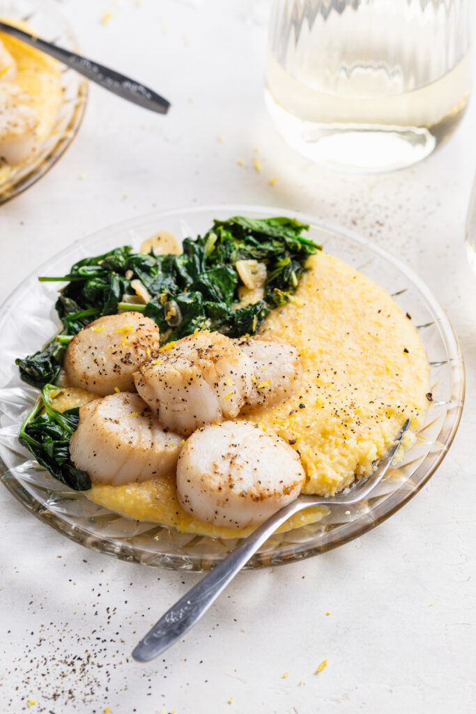 seared scallops recipe on a plate with white wine on the side