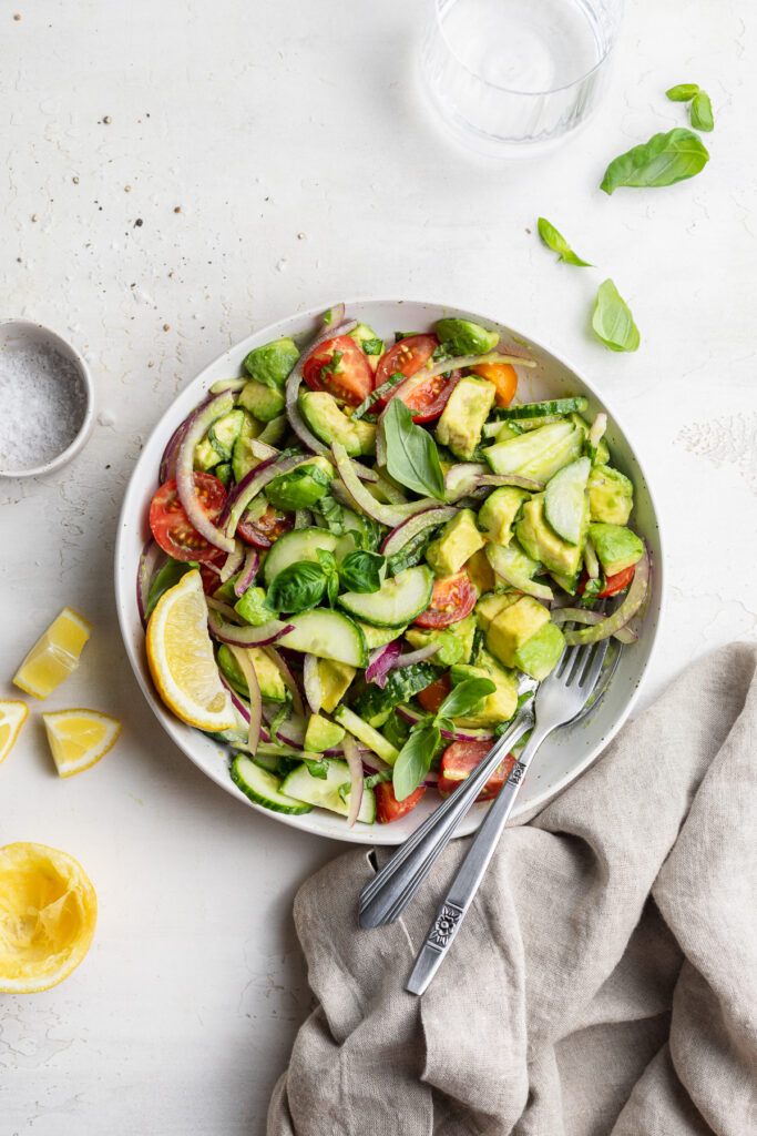 overhead image of avocado salad in a bowl with lemon on the side