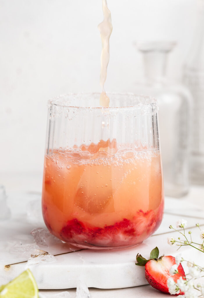 skinny strawberry margarita being poured from a cocktail shaker into a glass.