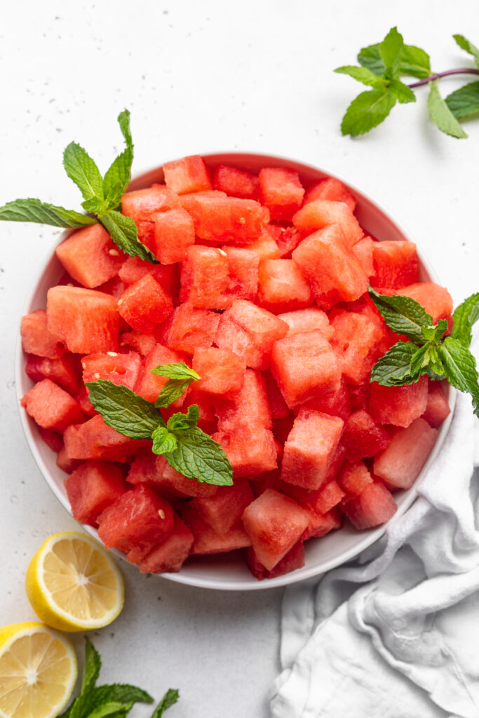 Watermelon cut into cubes in a bowl with fresh mint.