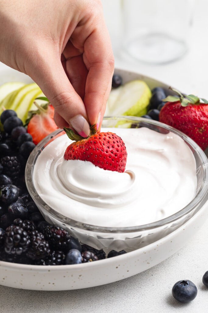 strawberry being dipped into marshmallow fruit dip.