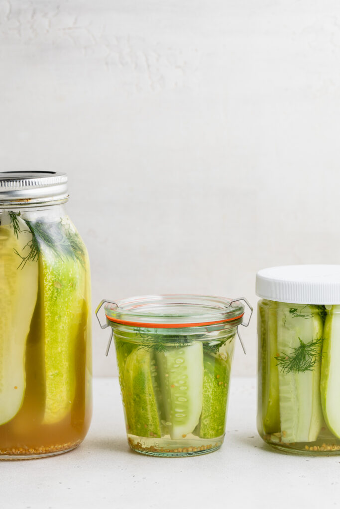 three jars of pickles line up on a table.