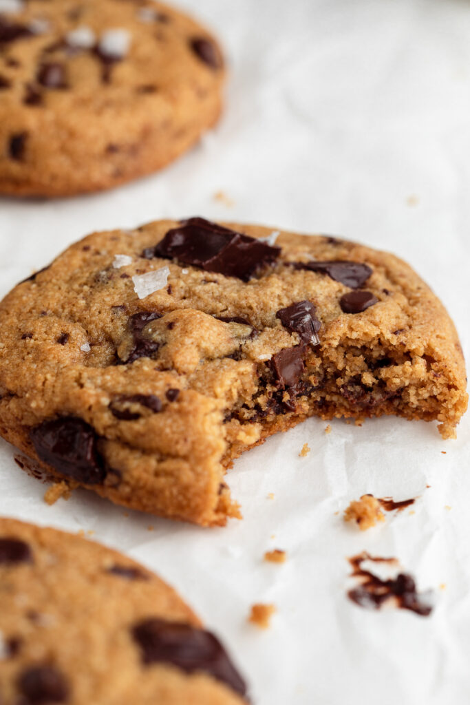 Close-up of a bite taken out of an gluten-free almond flour chocolate chip cookie topped with flaky sea salt.