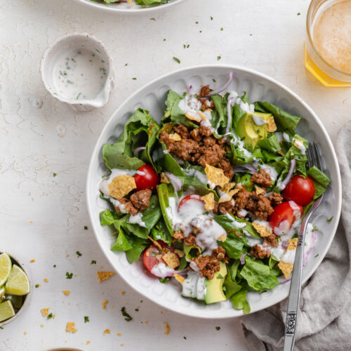 two bowls of taco salad with cialntro-lime dressing on the side.