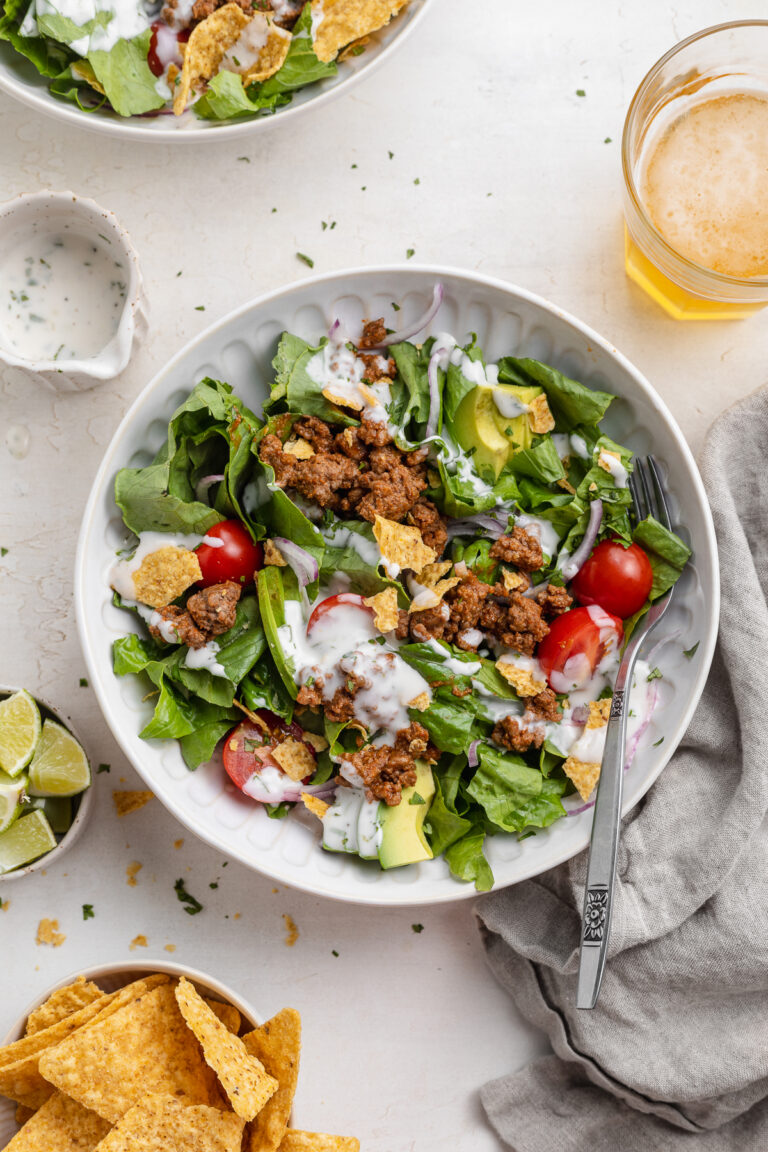 overhead image of a taco salad with chips and beer on the side.