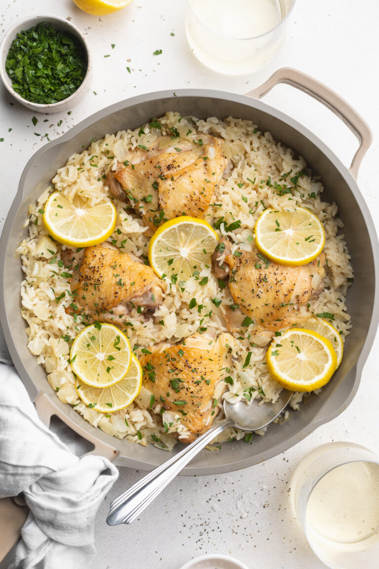 overhead image of chicken and rice in a pan with lemon slices on top.