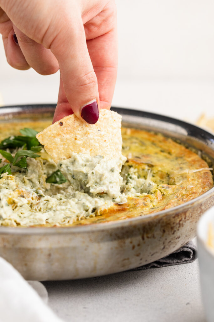 chip scooping vegan spinach artichoke dip