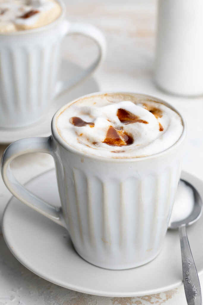 healthy caramel brulée latte in a mug with a spoon on the side.