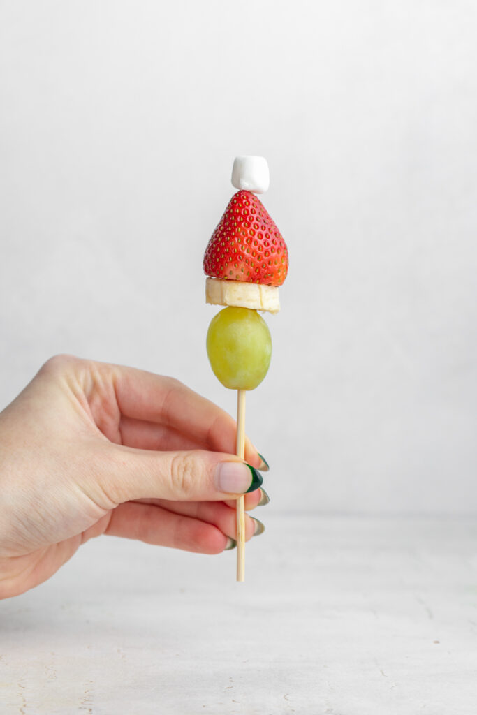 hand holding a grinch fruit kabob