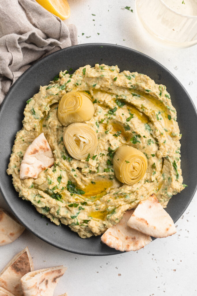overhead image of spinach artichoke hummus with pita on the side.