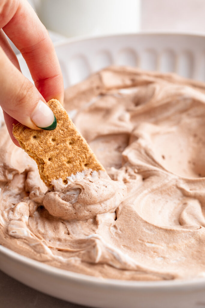 graham cracker being dipped into vegan hot chocolate dip.