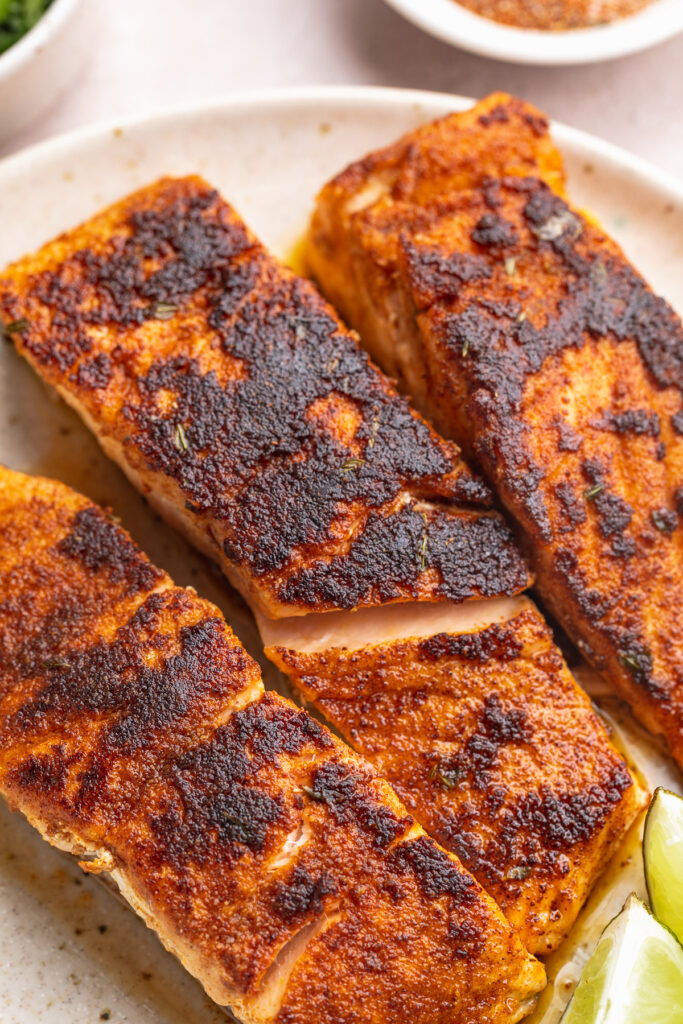 close-up image of three blackened salmon fillets on a plate.