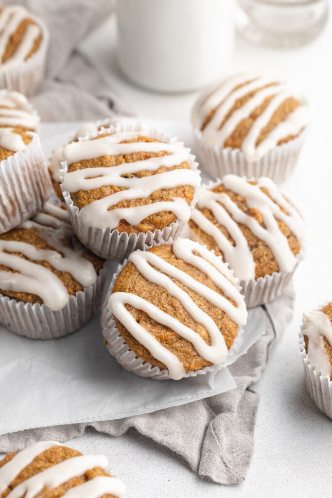 healthy carrot cake muffins with cream cheese icing on top and milk on the side.
