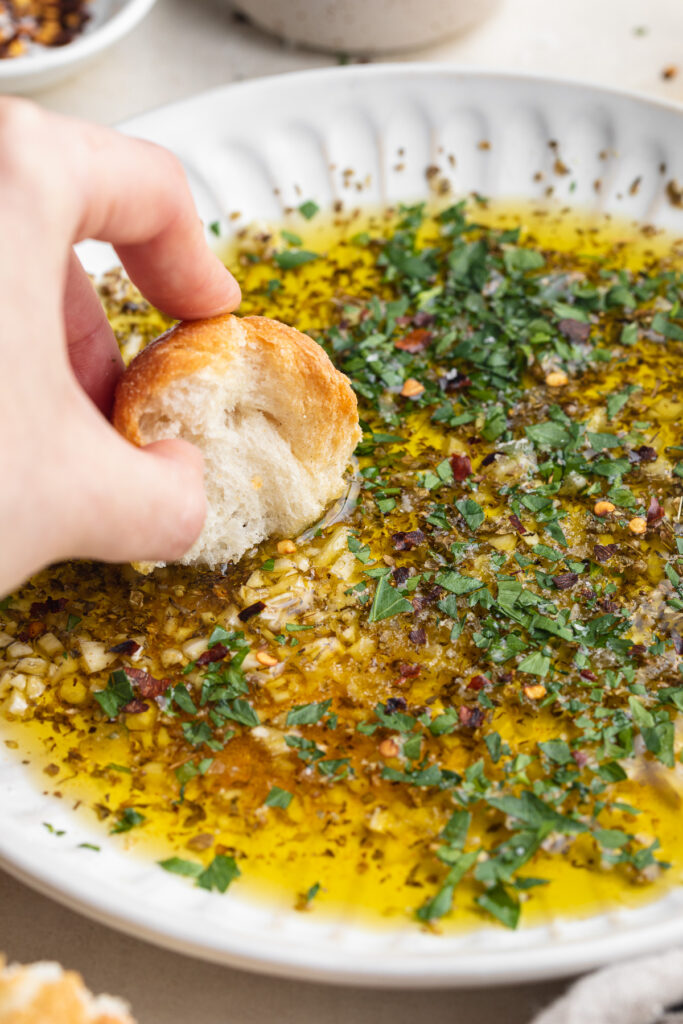 bread being dipped into garlic and herb olive oil dip.