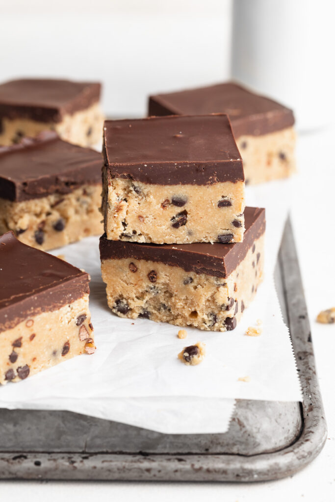 two healthy no-bake cookie dough bars stacked on top of each other on a baking sheet.