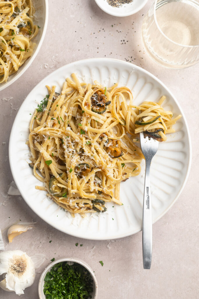overhead image of pasta with caramelized zucchini on a plate with a fork.