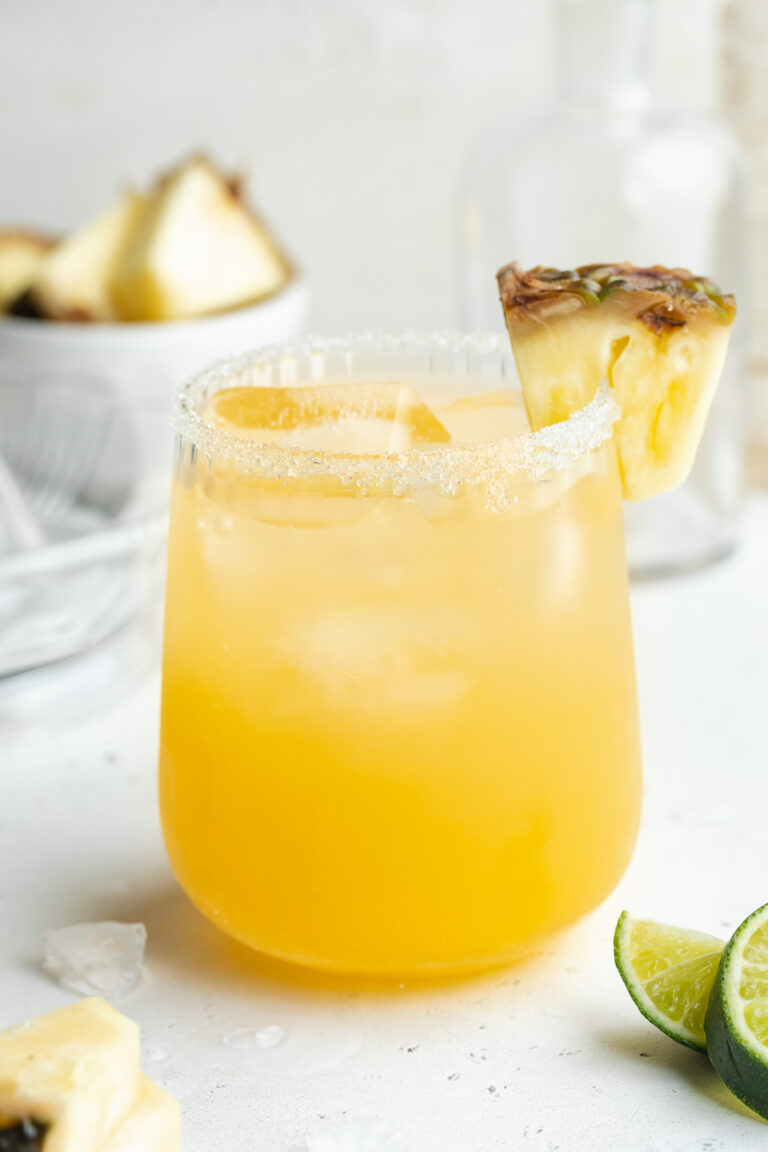 Pineapple margarita in a glass with a pineapple slice on the side.