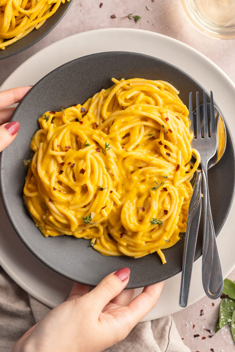 Placing down a bowl of vegan creamy butternut squash pasta.
