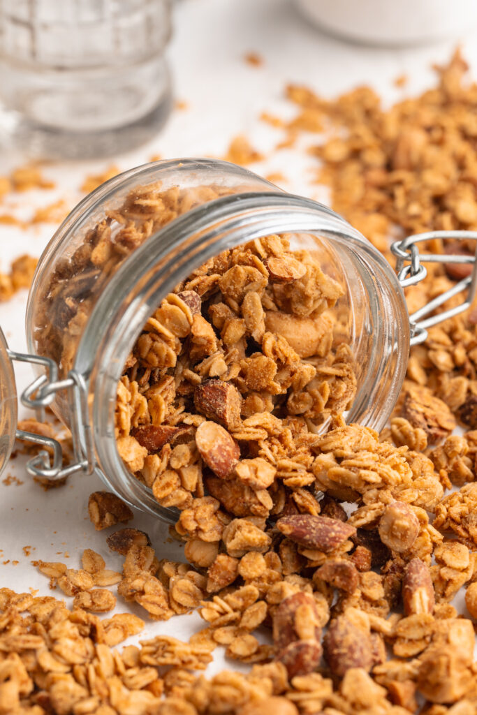Homemade granola pouring out of a glass jar.