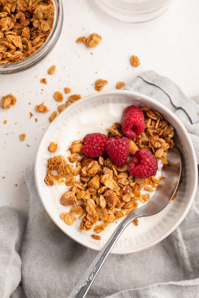 Homemade granola served with yogurt and fresh raspberries in a bowl.
