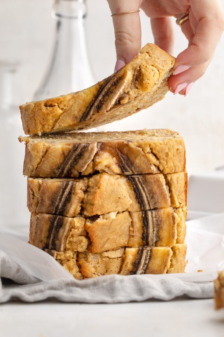 Stacked slices of 4 ingredient banana bread, with a hand lifting the top slice.