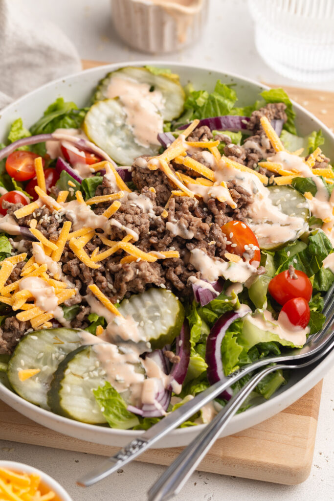 healthy big mac salad in a bowl with big mac sauce salad dressing on the side.