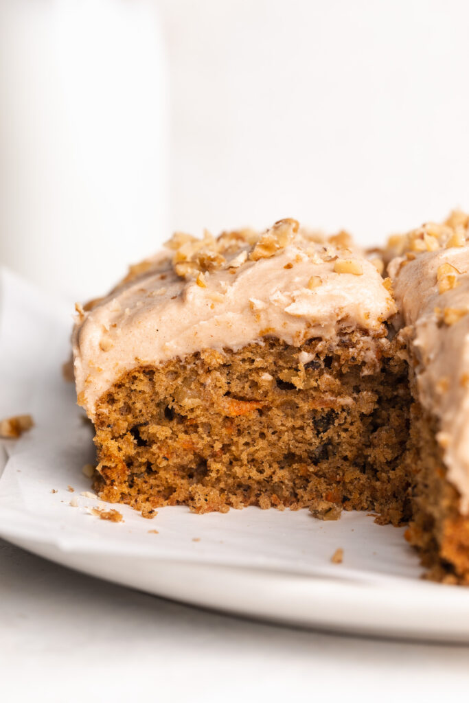 gluten free carrot cake with cinnamon cream cheese frosting cut into on a plate.