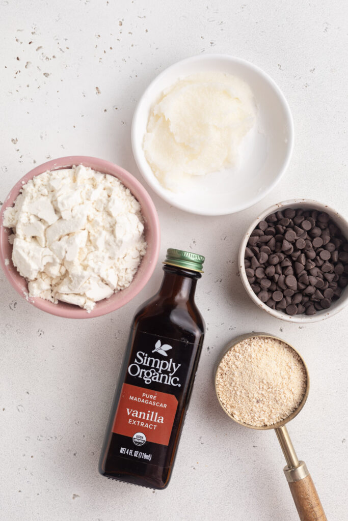 coconut oil, gluten free flour, vanilla extract, maple sugar, and chocolate chips on a table.