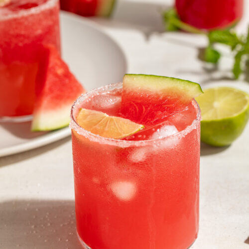 watermelon paloma in a glass with a lime slice and a small slice of watermelon.