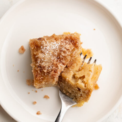 gluten-free cinnamon sugar apple cake slice on a small dish with a fork.