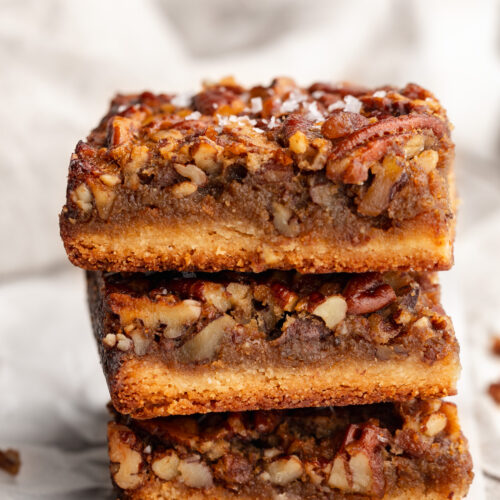 three healthy gluten free pecan pie bars stacked on top of each other.