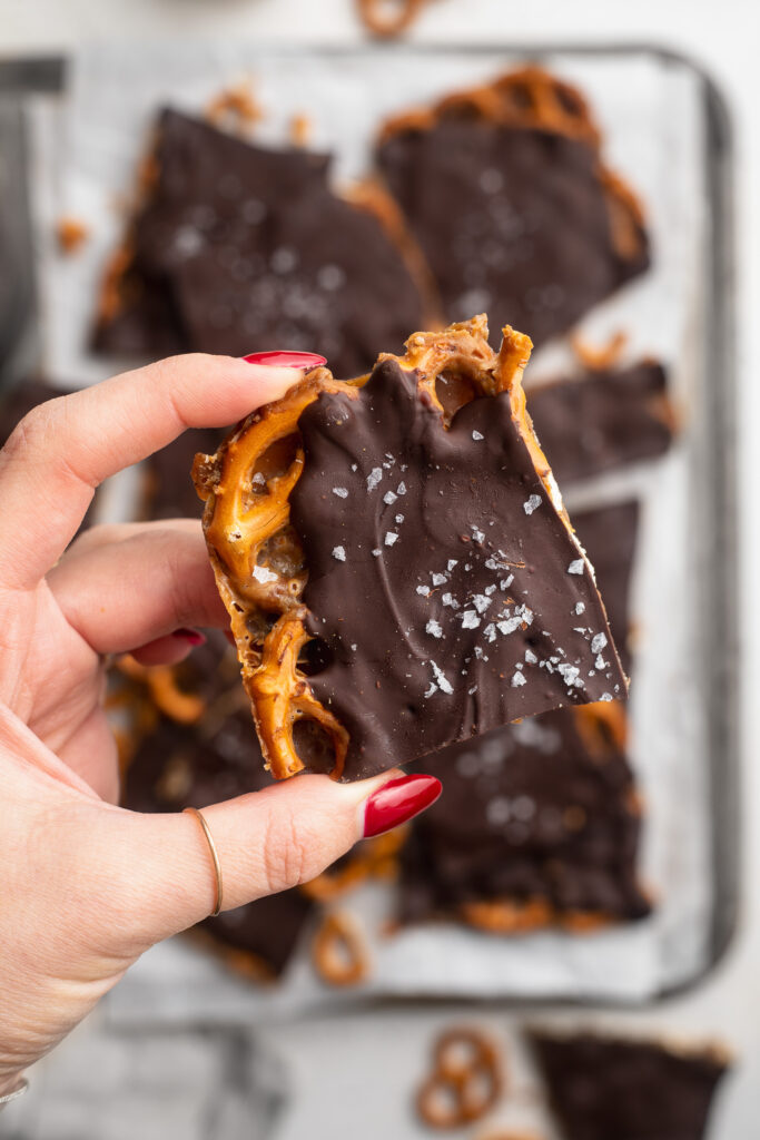 a piece of chocolate toffee pretzel bark with flaky sea salt on top.